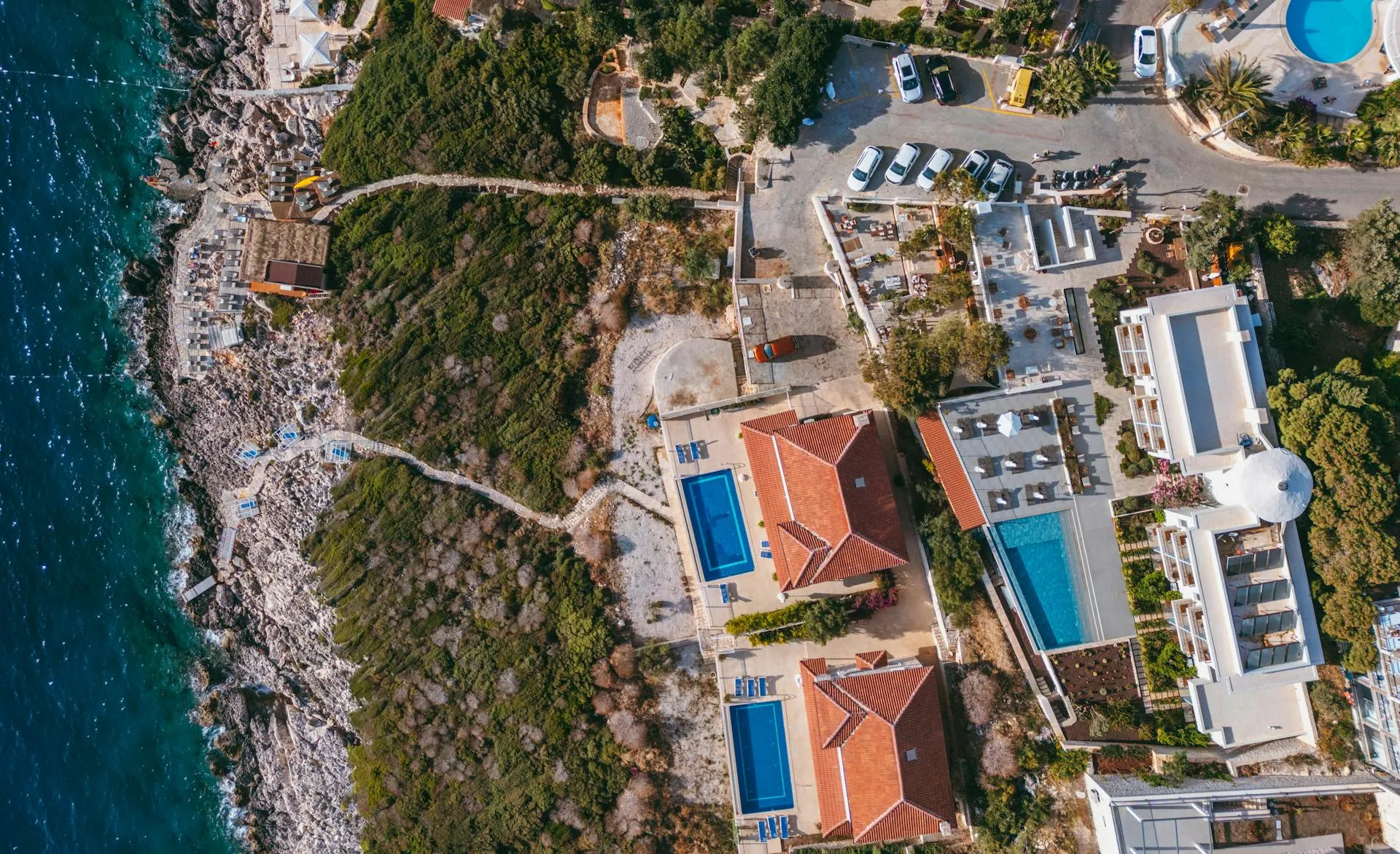 An aerial view of a cluster of coastal villas with private pools