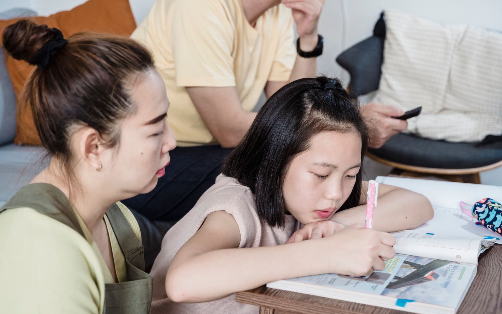 Parent and child reviewing marked schoolwork together with pencils and notebooks